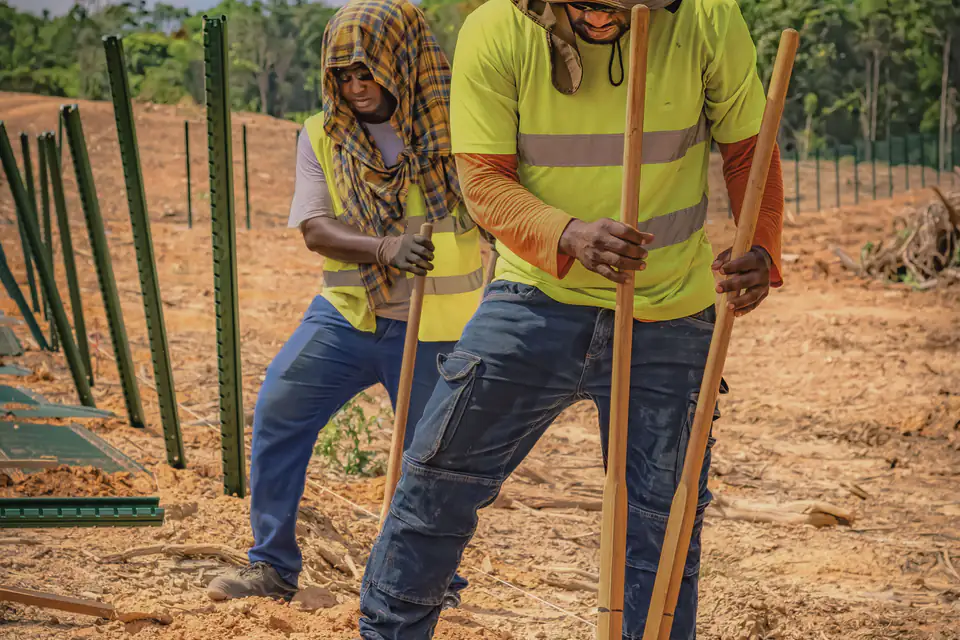Workers setting fence posts outdoors